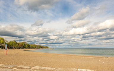 Puffy white spring clouds extent to the horizon over a tranquil Lake Ontario.  Shot in the Toronto Beaches looking east to Balmy Beach.  Room for text.