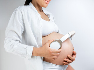 Pregnant woman music lover put the headphones on her belly to let Rebecca enjoy the music she likes. Girl waiting for a baby keeps headphones on her stomach