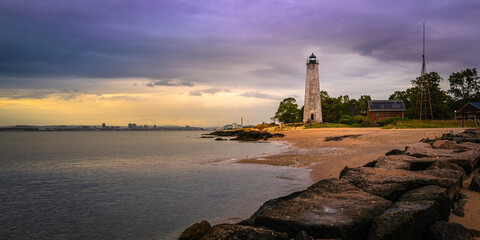 Fototapeta premium Dramatic cloudscape and lighthouse on the beach at New Haven Lighthouse Point Park in Connecticut