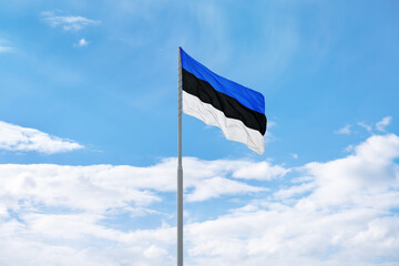 Flag of Estonia is waving in front of blue sky and clouds