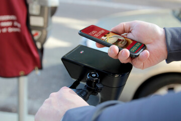 Man  on an electric scooter is ordering  food on  the internet using an app outside