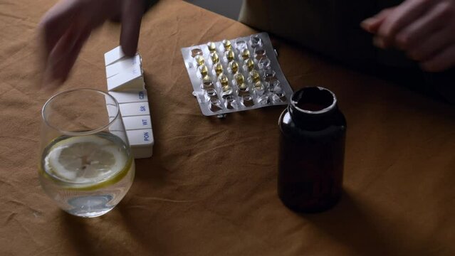 man sorts pills by day of the week in a sorter