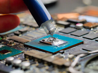 Technician applying thermal paste to a GPU on laptop motherboard. Cooling upgrade concept. Graphics...