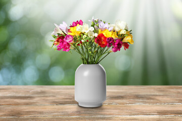 Vase with beautiful freesia flowers on wooden table outdoors. Bokeh effect