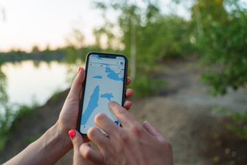 A couple of tourists on a camping trip, looking for the way by GPS on a smartphone. An application...