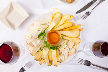 Cheese plate served with honey and decorated with herb on wooden table, on white background.