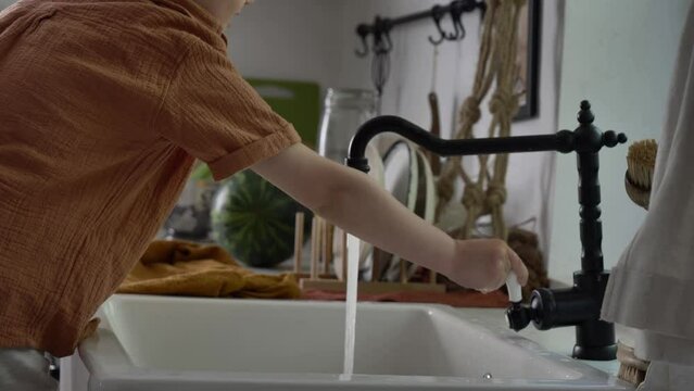 Little kid wahsing up a lemon in kitchen