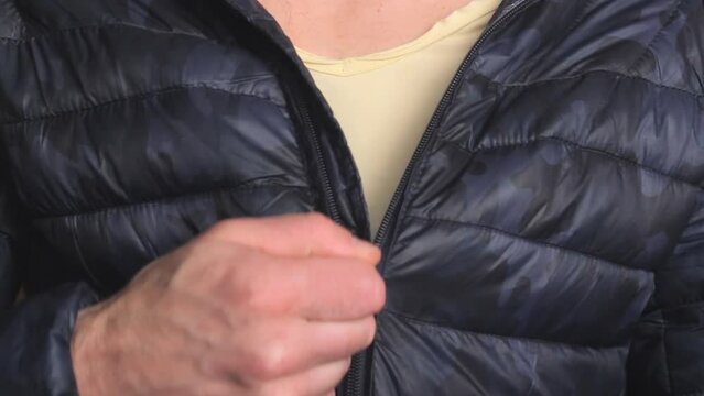 Man dressing to go outside, closing zipper on jacket. Body close up