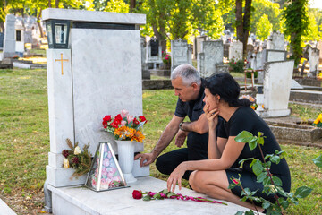 Mature couple in grief, in black clothes, holding a flower and mourning a deceased loved one on...