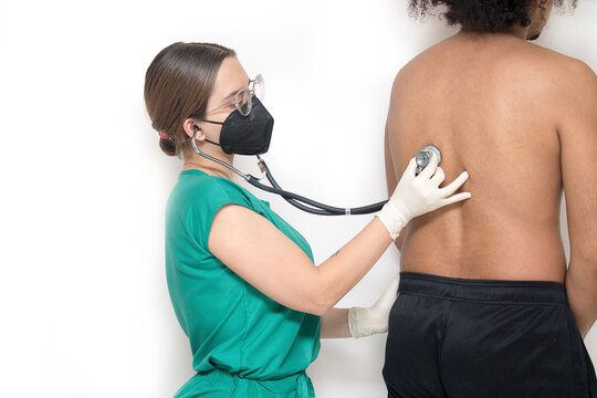 Nurse in green surgical uniform with stethoscope checking male patient from behind. Image with white copy space