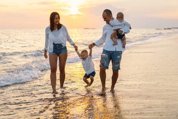 Happy family having fun playing beach in summer vacation on the beach. Happy family and vacations concept. Seascape at sunset with beautiful sky. Family on the beach.