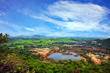 Fototapeta premium High angle view of fertile farming community in rural Thailand under bright blue sky and white clouds.