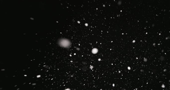 White snow falling against dark background