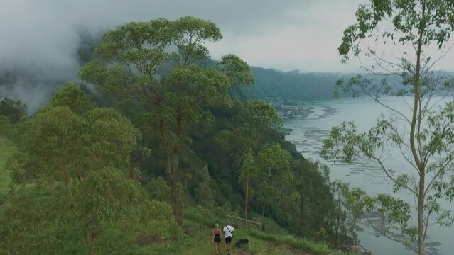 Tourist couple visiting breathtaking viewpoint overlooking lake Batur in Bali, aerial