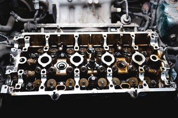 Fototapeta na wymiar Disassembled car engine in oil. Cylinder head of an automobile engine. Inside the car being repaired. Sixteen valves. Car maintenance