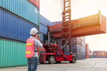 Back view of male worker at commercial dock, wearing safety helmet and using radio communication...