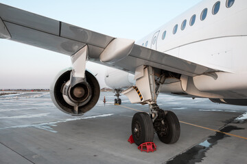 White passenger airplane on the airport apron. Close-up of rear wing and main landing gear