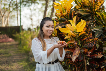 Portrait of young mexican woman next to garden plant. © sandor