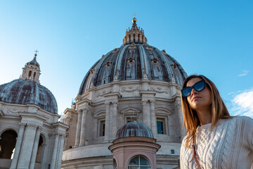 Tourist woman in sunglasses with detailed close up view on Michelangelos Dome of St Peter Basilica in Vatican City, Rome, Lazio, Europe, EU. Landmark of Papal Basilica of Saint Peter on sunny day