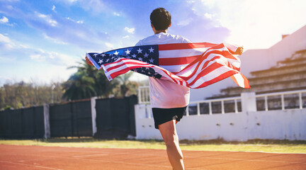 Young man runner with American flag cover his back running, celebrates the victory in racetrack....