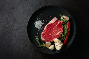 Raw beef meat steak with rosemary, garlic, salt, and pepper.