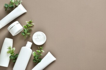Natural cosmetics, skincare product - cream, lotion and micellar water on a beige background with green leaves. Flat lay composition with copy space.