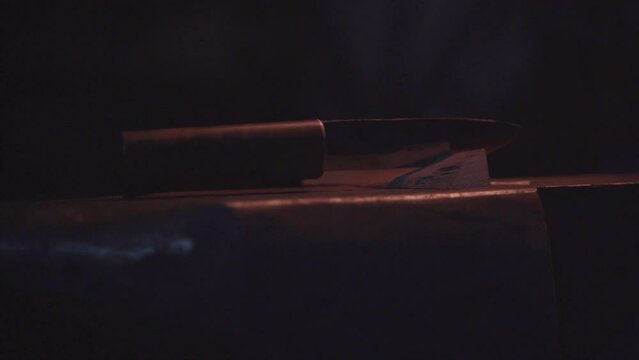 Damascus steel knife by blacksmith in smithy workshop.