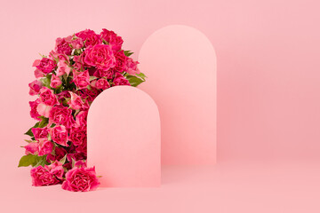 Elegant arch of fresh roses, blank rounded spaces as two podium mockup on pink stage for presentation cosmetic products, copy space. Flowers template for wedding invitation, advertising, design.
