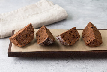 Chocolate cake on dark brown board on gray textured background. Delicious homemade food