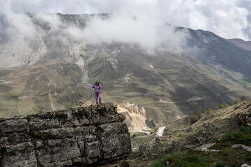 a woman tourist in a pink suit poses against the backdrop of beautiful mountains of gorges and...
