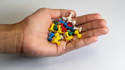 Handful of colorful push pins in hand isolated on white background