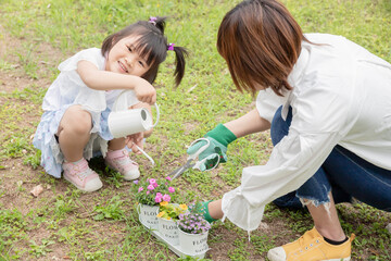 女性と子供が一緒に花の手入れや水やりをしている