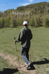 A person walks along the road doing Nordic walking, hiking in the mountains, summer holidays in...