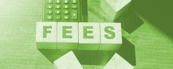 Wooden Blocks with the text: Fees and calculator on wooden table. Taxes and fees business financial...