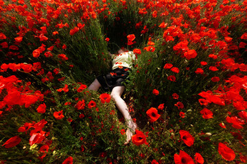 woman, lying dead in a yellow shirt in a field of red poppy flowers, copy space