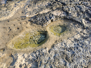 The coast of the Mediterranean Sea, clear water, long-hardened lava, in the recesses of which there is sea water. Background. It looks like an alien landscape.