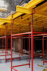 Fototapeta na wymiar construction formwork for concrete pouring at construction site. Concrete slab construction. Plywood sheets, yellow timber beams and red steel supports.