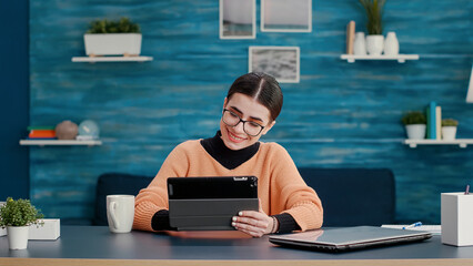 University student doing research work on digital tablet at home, planning project for homework assignment. Person using device to create lecture report for online school course, remote learning.