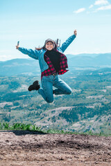 young pretty woman jumping at the top of the mountain