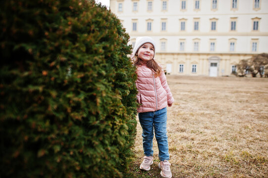 Girl Wear Pink Jacket Stand Near Bush At Valtice Palace, Czech Republic.