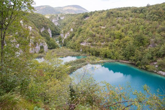 Plitvice Lakes National Park, Croatia, Europe: Panoramic view to the lower lakes with its beautiful turquoise water and crossing or connecting boardwalks between steep slopes