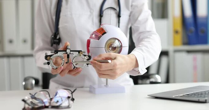 Doctor showing glasses for checking vision and artificial model of human eye closeup 4k movie slow motion