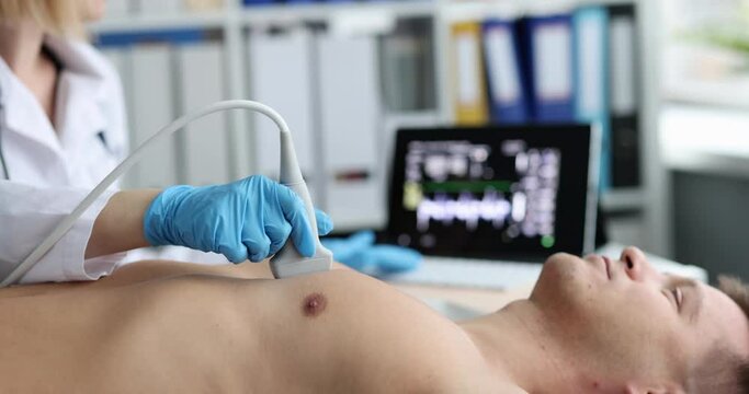 Doctor cardiologist conducting ultrasound examination of heart of young man 4k movie