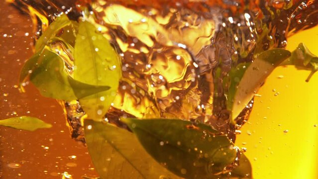 Super Slow Motion Shot of Pouring Tea into Whirl with Green Leaves at 1000fps.