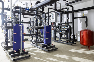 Industrial basement with heating pipes, pressure gauges, valves and heat exchangers
