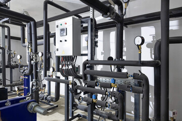 Industrial basement with heating pipes, pressure gauges, valves and heat exchangers