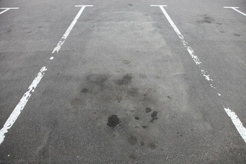Empty parking lot with black oil stains from cars on the asphalt