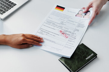 Close-up shot of unrecognizable consular officer giving back visa application form with rejected...