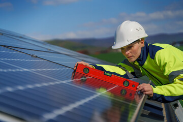Woman engineer installing a solar photovoltaic panels on roof, alternative energy concept.
