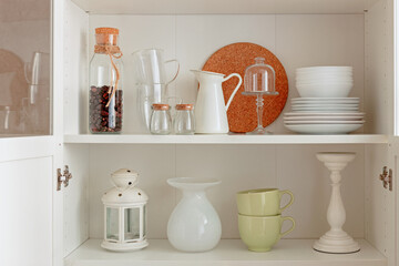 Cabinet with crockery, .kitchen utensils on the shelf. Order in kitchen